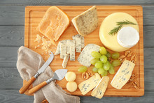 Assorted Sliced Cheese With Grape And Nuts On Wooden Board