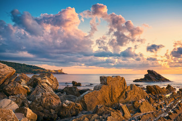 Wall Mural - Rocks and buildings on the sea at sunset. Livorno, Tuscany riviera, Italy