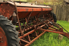 Old Grunge Seeding Machines Standing On The Grass After The End Of Sowing. Old Equipment. Decline In Agriculture