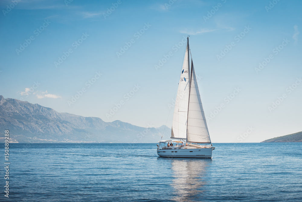 Sailing yacht in the sea against the backdrop of mountains - obrazy, fototapety, plakaty 