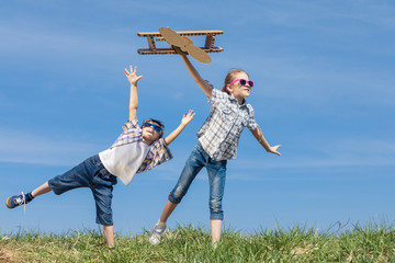 Wall Mural - Little kids playing with cardboard toy airplane in the park at the day time.