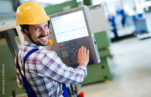 Fotografie, Obraz Industry Worker entering data in CNC machine at factory