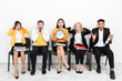 © Drobot Dean - Confused colleagues sitting in office holding clock.
