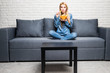 © F8  \ Suport Ukraine - Young woman watching TV and eating chips at home