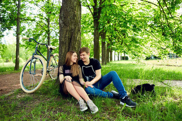 A loving couple is resting by  tree on the grass in the park.