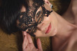 Beautiful, sexy mysterious woman - stranger in the lace mask with short black hair and playful eyes smiling, flirting in a wine cellar in the old castle