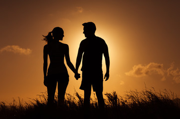 Relationship concept. Silhouette of man and woman feeling in love holding each others hands.