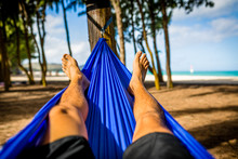 Man Relaxes In Hammock At Beach Facing The Ocean