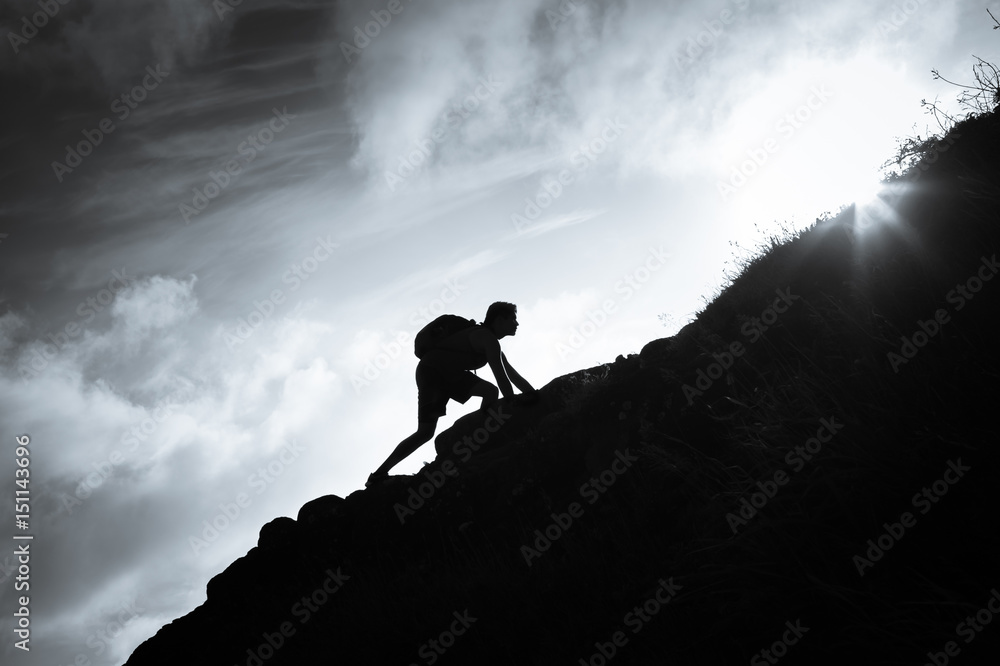 Success, life goals, and taking risk concept. Man climbing up a edge of a mountain.  - obrazy, fototapety, plakaty 