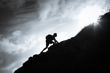 success, life goals, and taking risk concept. man climbing up a edge of a mountain.