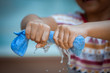 Child hands squeeze wet blue towel and water drop