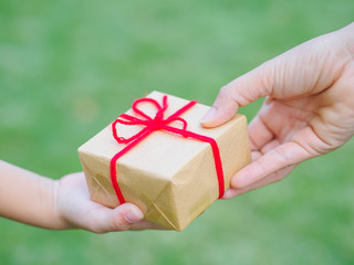 Wall Mural - holidays, present, christmas, childhood and happiness concept - close up of child and mother hands with gift box over green background