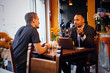 © Fxquadro - Two men talks and using a laptop in a restaurant.