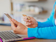 © Siam - Pretty Young womans hands holding a credit card and using smartphone and laptop computer for online shopping. Online payment. Female working on smart phone laptop in a cafe.