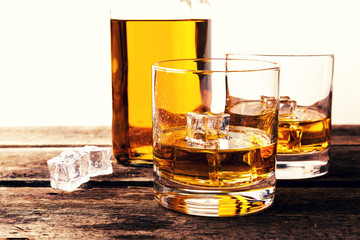 Wall Mural - whiskey glasses and bottle on wooden table against white background