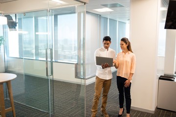 Wall Mural - Businesswoman with male colleague using laptop in office