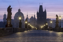 Street Lanterns And Old Statues Frame The Historical Buildings On Charles Bridge At Dawn, Prague, Czech Republic