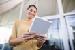 © WavebreakMediaMicro - Low angle view of smiling businesswoman using tablet in office