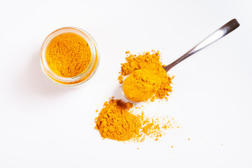 Turmeric in glass jar. Heap. Spoon. Isolated on white.  Top view.