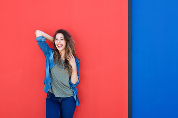 Wall Mural - cheerful young woman against red wall