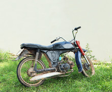 An Old Motorcycle Parked Against Wall