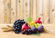 Grapes, dates, figs, garnets, barley and wheat on wooden table on a wooden background with space of text