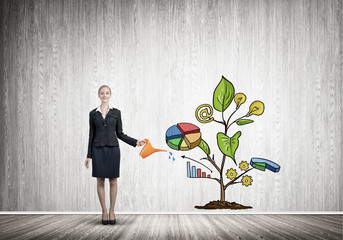 Young businesswoman in empty room watering drawn growth concept with can