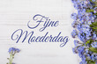 Mother's day card with Dutch words: Happy Mother's day. Blue flowers frame on white wooden background