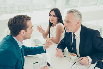 Business partners are discussing the  financial growth of their company. Young one is existing on his ideas, old one is focused and listening