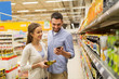 © Syda Productions - couple with smartphone buying olive oil at grocery