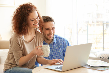 Wall Mural - Happy young couple with laptop at home