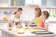 © Africa Studio - Young woman and her daughters cooking in kitchen