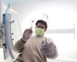 dentist with green mask and tools for cleaning the teeth
