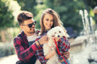 © Mediteraneo - Young couple with puppy. Portrait of attractive happy smiling young woman and man holding cute little dog, summer park outdoor.
