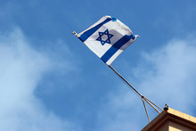 Israeli Flag On A Rooftop Against Blue Sky Background
