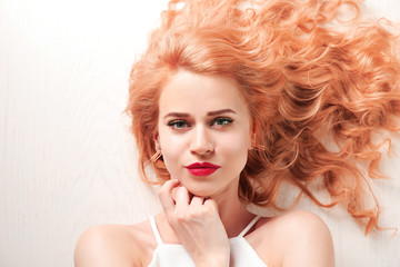 Wall Mural - Portrait of young woman with blonde hair on white wooden background