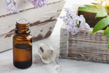 Bottle of essential oil with fresh lilac flower