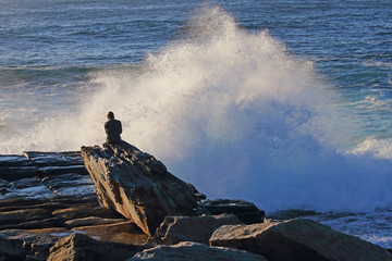 Canvas Print - a person sitting by the beach watching wave breaks.