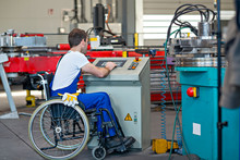 Disabled Worker In Wheelchair In Factory And Colleague