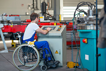 disabled worker in wheelchair in factory and colleague