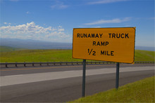 A Yellow Rectangular Roadsign With The Message "Runaway Truck Ramp 1/2 Mile" Written Upon It. 