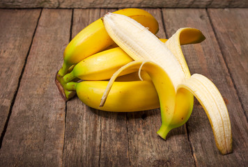 Wall Mural - Bundle of bananas and a sliced banana on vintage wooden background, selective focus