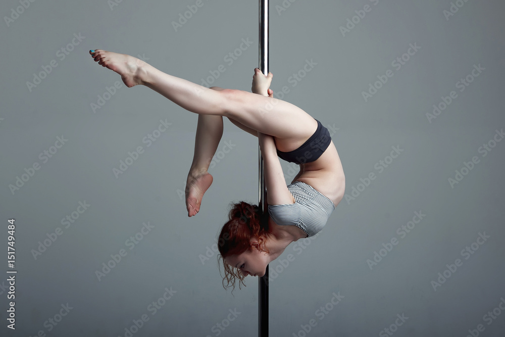 Young woman exercise pole dance gray background - obrazy, fototapety, plakaty 