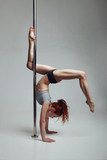 Young woman exercise pole dance gray background