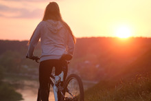 Girl Riding A Bike In Sunset
