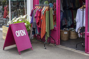 Brightly colored Open sign outside a shop selling clothes, on a sunny day in London, UK