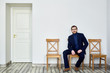© pressmaster - Man in suit sitting on one of chairs by wall