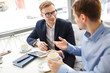 © pressmaster - Portrait of two business people talking at table in cafe smiling and gesturing actively discussing work