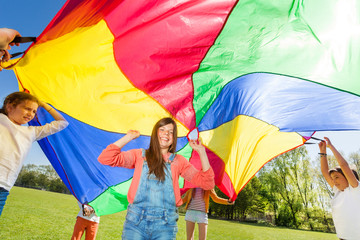 Wall Mural - Happy friends playing rainbow parachute in summer