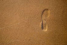 A Trace Of Shoes On A Wet Yellow Sand